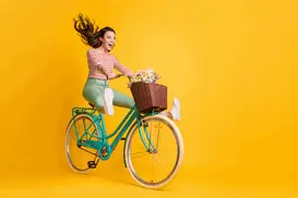 A cheerful and sunny girl on a bike, with a basket of flowers in front. Living life to the fullest, she chooses studies that best match her energetic personality!